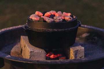 Black durch oven with glowing coal on top and underneath.