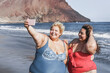 © DisobeyArt - Curvy women friends taking selfie on the beach - Focus on faces