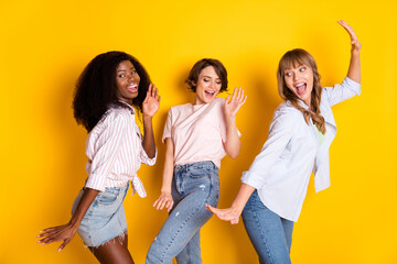 Wall Mural - Portrait of three carefree cheerful ladies open mouth smile have fun partying isolated on yellow color background