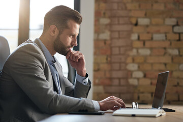 Thoughtful young businessman at work with computer