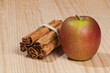 Red apple with a cinnamon stick; photo on wooden background.