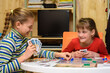 © madhourse - Two girls joyfully laugh while playing board games at the table