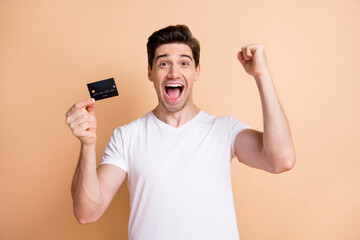 Sticker - Portrait of delighted handsome guy fist up open mouth celebrate hold debit card isolated on beige color background