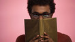© LIGHTFIELD STUDIOS - african american teenager obscuring face with book isolated on pink