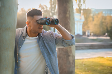 Wall Mural - Jealous man with binoculars spying on ex girlfriend in park