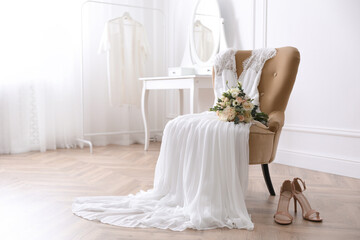 Elegant wedding dress, shoes and bouquet in room