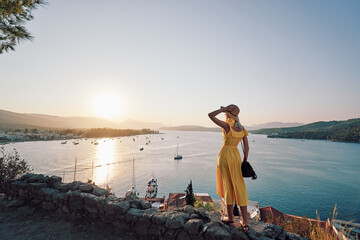 Wall Mural - Enjoying vacation in Greece. Young traveling woman enjoying sunset on sea view point.