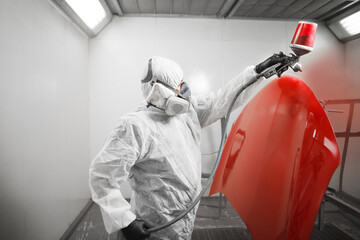 Wall Mural - Automobile repairman painter in mask and protective workwear painting car body in paint chamber.