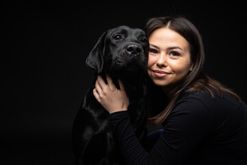 A girl holds a Labrador Retriever dog in her arms.