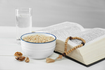 Wall Mural - Oatmeal, rosary beads, Bible and glass of water on white table. Lent season