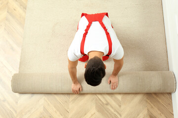 Sticker - Worker rolling out new carpet flooring indoors, top view