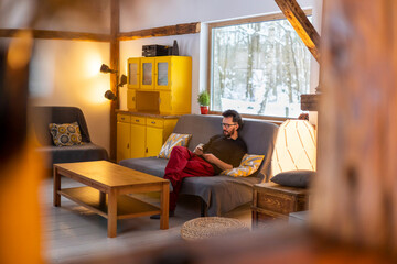 Young man sitting on couch at home, using smartphone
