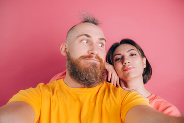 Wall Mural - Close up portrait of young, caucasian, attractive, lovely, cute, sweet, smiling, positive couple in casual making selfie on mobile phone on pink background