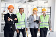 © sofiko14 - Group of multiethnic confident male and female architects and engineers in hardhats inspecting unfinished office building together and discussing plan details