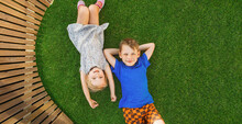 Children Lying On The Green Grass In The Garden. The Interaction Of The Children