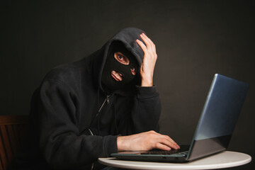 A dangerous masked hacker with a hood cannot infiltrate the data servers and infect them with viruses. Caught the criminal through a laptop.