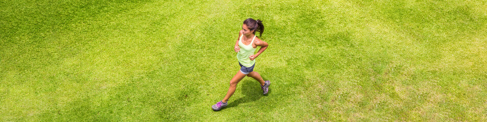 Wall Mural - Runner woman running on grass background outdoor training for marathon. Top view of Asian sport athlete girl on hiit run. Banner.