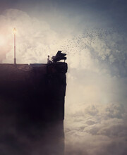 Person Silhouette On The Edge Of A Cliff Sings And Plays A Piano Song, As Flock Of Birds Flying Out Of The Musical Instrument. Surreal And Inspirational Scene Above Clouds. Adventure And Music Concept