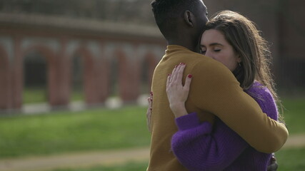 Interracial couple empathic embrace. Young woman romantic connection with partner outside