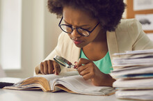 Closeup Portrait Young African American Woman Analyst Expert With Magnifying Glass Searching Information In Document Sitting At Desk With Paper Folder Stack In Comfort Office. Research Work