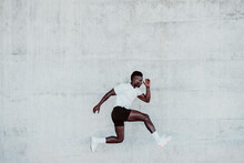 Young Male Athlete Jumping By White Wall