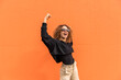 © VISTA by Westend61 - Cheerful woman with arms raised standing against orange wall
