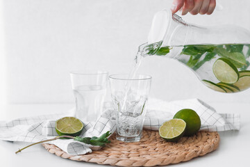 Poster - Detox water with lime fruit. Hand pouring lime fruit water from jug into glasses