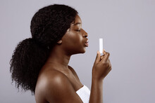 Attractive Black Woman Holding Hygienic Lip Balm In Hand Over Gray Background