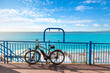 A luxury bicycle is parked along a railing on the Promenade des Anglais with the Bay of Angels and beach behind on the French Riviera in Nice, France.