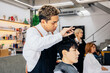 Asian male customer getting hair cut with hairdresser in salon. Fashionable barber using a scissor to trim client hair in barbershop