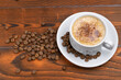 © Aleksandr Tretiakov - white cup with cappuccino and coffee beans on wooden background
