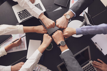 Team of business people putting fists together in office