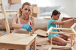 © astrosystem - Mother and daughter painting and assembling furniture in new apartment, moving in and being hardworking.