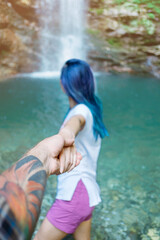 Sticker - Young woman holding man's hand and leading him to waterfall, point of view. Focus on hand. Back view.