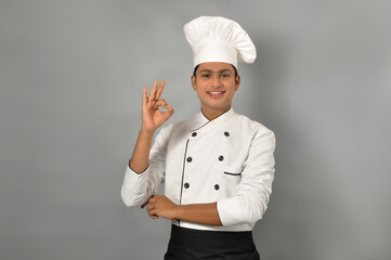 Happy male Indian chef showing ok gesture with one hand over grey background, profession and people concept