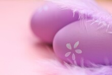 Easter Holiday.Easter Lilac Eggs  And Purple Feathers On A Delicate Light Pink Background.Festive Easter Background In Pastel Purple Colors. Copy Space