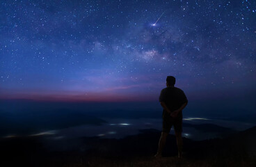 Wall Mural - colorful night sky with stars and silhouette of a standing man on the stone. blue milky way with man