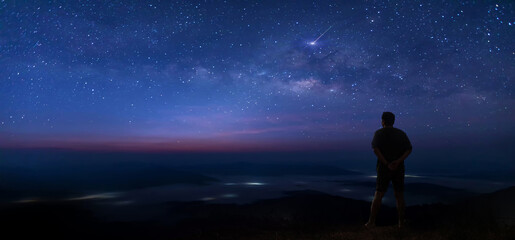 Wall Mural - colorful night sky with stars and silhouette of a standing man on the stone. blue milky way with man