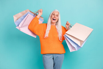 Poster - Photo of joyful excited elderly woman raise bags happy customer smile isolated on pastel teal color background