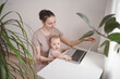 © Алина Троева - Young mother work studying from home with laptop computer during quarantine, little cute toddler baby on lap. Home office, parenthood. Remote work, distance education. Video conference virtual event.