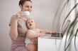 © Алина Троева - Young mother work studying from home with laptop computer during quarantine, little cute toddler baby on lap. Home office, parenthood. Remote work, distance education. Video conference virtual event.