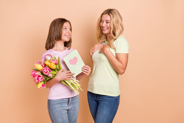 Poster - Photo of blonde haired mother and small girl kid wear jeans hold card flowers celebrate isolated on beige color background