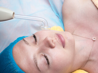 High frequency facial treatment promoting the blood circulation of the skin and disinfecting effect. Spa salon indoors