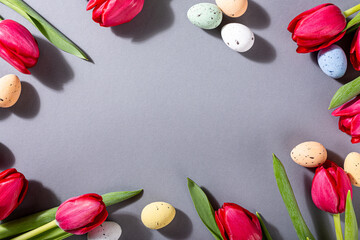 Wall Mural - Pink tulips and quail eggs over gray background, Easter holiday background. Greeting card concept with copy space. Top view, flat lay.