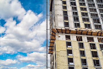 Wall Mural - Residential high-rise building under construction. Unfinished house on a construction site with cranes.