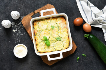 Wall Mural - Zucchini gratin with bechamel sauce and parmesan on a dark concrete background. Summer pie with zucchini.