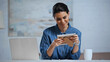 © LIGHTFIELD STUDIOS - pleased woman holding photo frame near laptop on desk