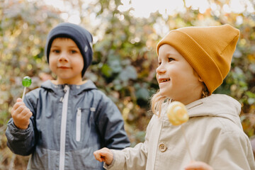 Wall Mural - beautiful couple of children, boy and girl have a sincere friendship with each other and have fun and pose for a photo on a walk in the park