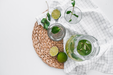 Poster - Detox water with lime fruit and mint leaves in jar and glasses. Flat lay, top view