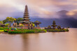 © Olga - Pura Ulun Danu Bratan temple in Bali island. Beautiful balinese temple during sunrise. Balinese landmark. Cloudy sky. Water reflection. Slow shutter speed. Bratan lake, Bali